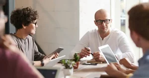 Informally dressed office workers sitting round a meeting table