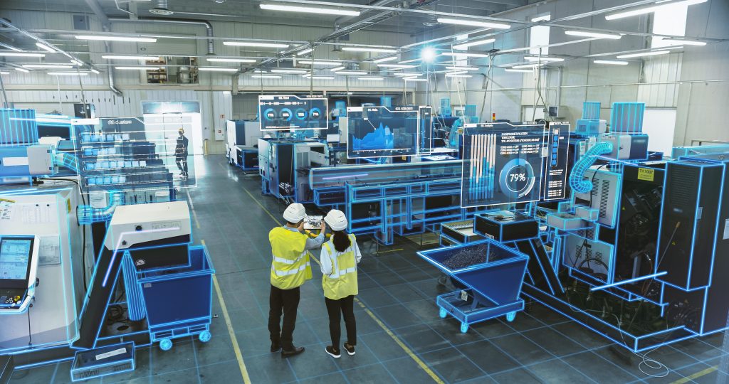 Two workers in hi visibility jackets seen from a distance standing on a factory floor